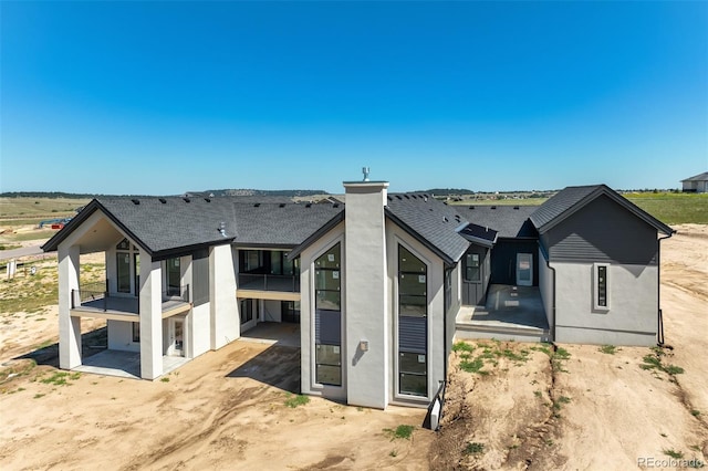 back of property with a patio, stucco siding, roof with shingles, and a balcony