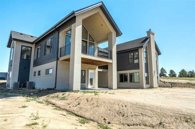 back of house featuring central air condition unit, stucco siding, and a balcony