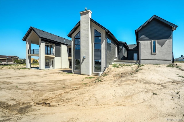 back of house featuring a balcony and stucco siding
