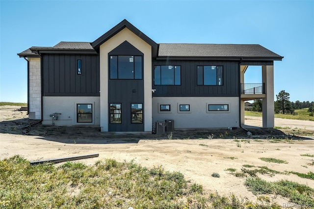 exterior space with roof with shingles, board and batten siding, and central AC