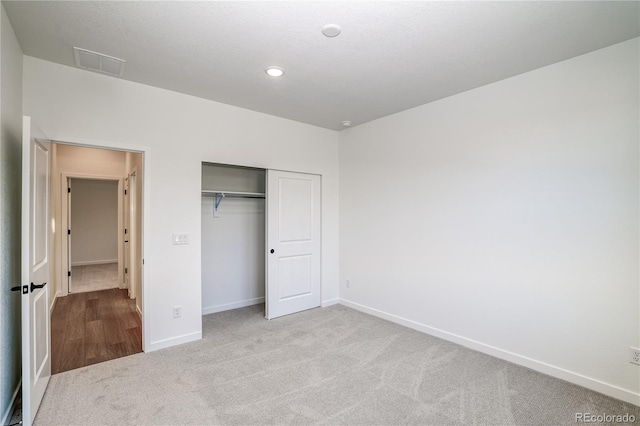 unfurnished bedroom with light colored carpet and a closet