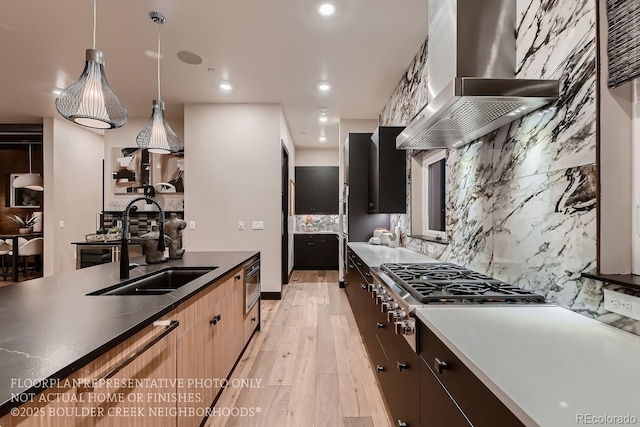 kitchen featuring pendant lighting, sink, extractor fan, stainless steel gas cooktop, and light wood-type flooring