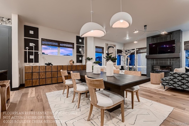 dining area featuring a tiled fireplace, light hardwood / wood-style floors, and built in features