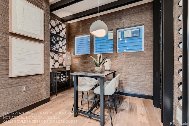 dining space with light wood-type flooring and beam ceiling