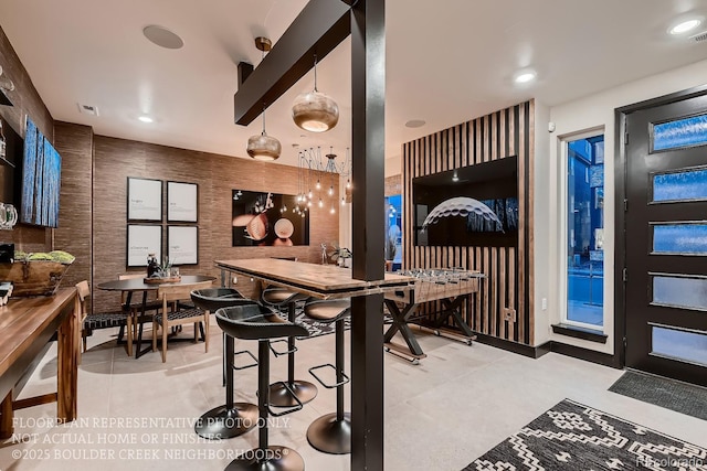 kitchen featuring beam ceiling, light tile patterned floors, and decorative light fixtures