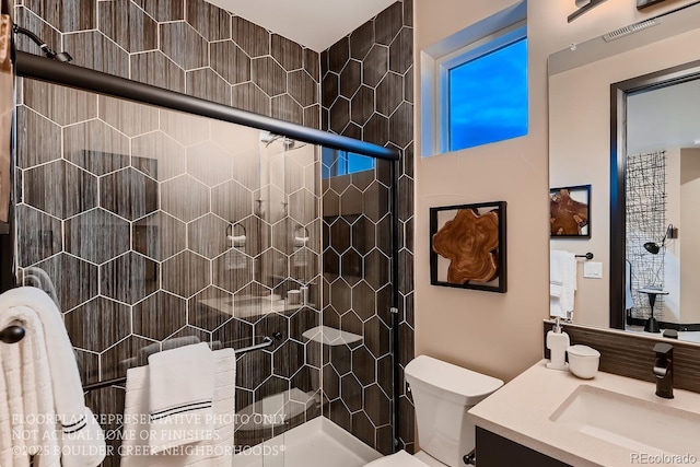 bathroom with vanity, a shower with shower door, and toilet