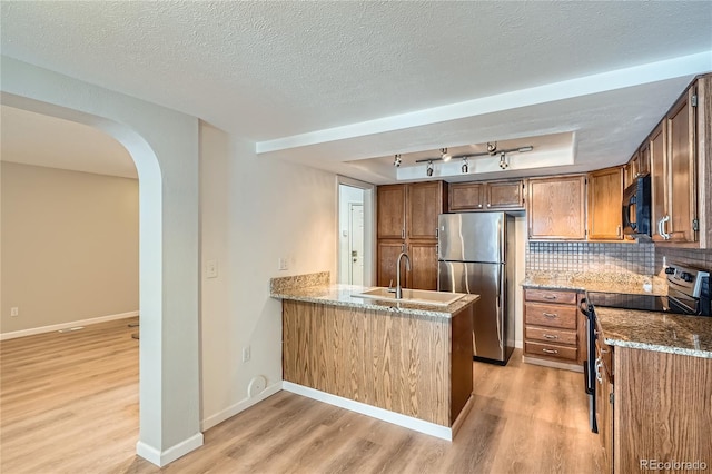 kitchen featuring a raised ceiling, sink, light hardwood / wood-style flooring, decorative backsplash, and appliances with stainless steel finishes