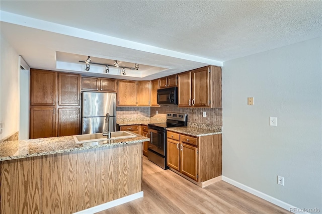 kitchen featuring kitchen peninsula, appliances with stainless steel finishes, decorative backsplash, a raised ceiling, and sink