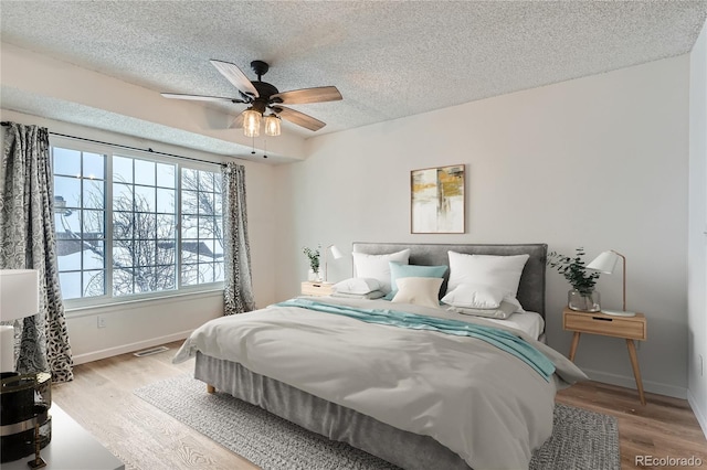 bedroom featuring hardwood / wood-style floors, ceiling fan, and a textured ceiling