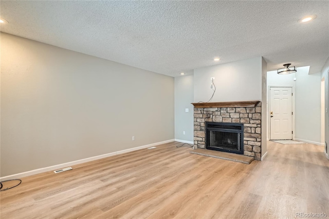 unfurnished living room featuring a fireplace, a textured ceiling, and light hardwood / wood-style flooring