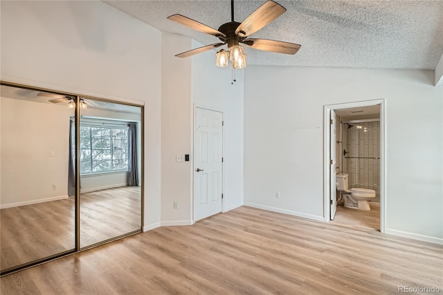 unfurnished bedroom featuring ensuite bathroom, vaulted ceiling, ceiling fan, a textured ceiling, and a closet