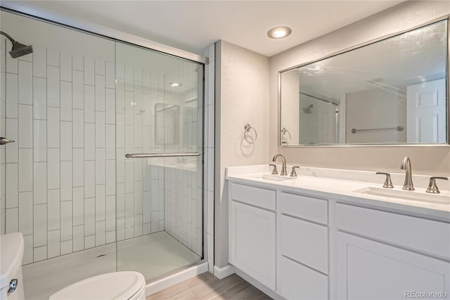 bathroom with hardwood / wood-style floors, vanity, toilet, and walk in shower