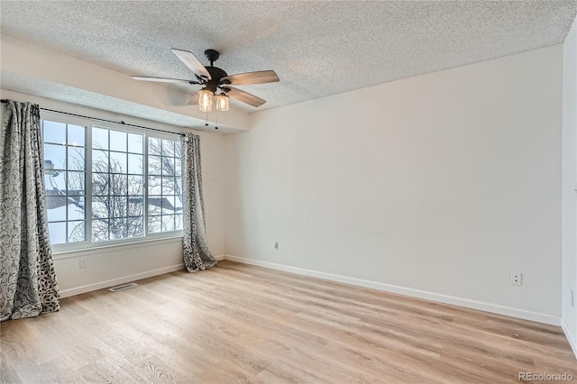 spare room featuring a textured ceiling, light wood-type flooring, and ceiling fan