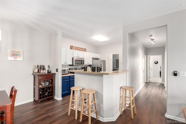 4451 S Ammons St Unit 5-307, Littleton, CO 80123 - kitchen featuring dark wood-type flooring, a breakfast bar, stainless steel appliances, and blue cabinetry