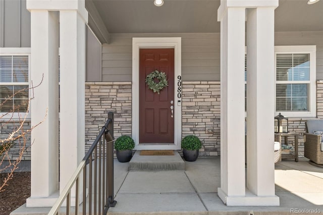 entrance to property featuring a porch and brick siding