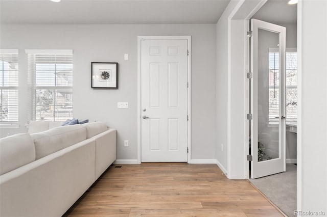 entryway with a healthy amount of sunlight, light wood-style floors, and baseboards