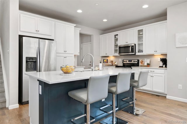 kitchen featuring stainless steel appliances, light wood-type flooring, white cabinetry, and glass insert cabinets