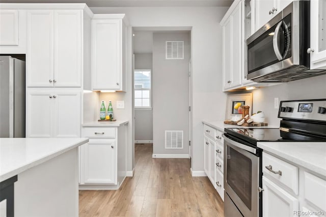 kitchen featuring stainless steel appliances, light countertops, visible vents, and white cabinetry