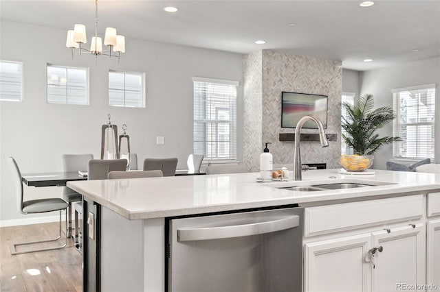 kitchen featuring recessed lighting, a sink, open floor plan, light countertops, and stainless steel dishwasher