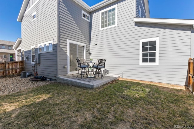 rear view of house with a fenced backyard, a lawn, and a patio