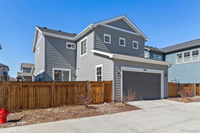 view of front of home with an attached garage, fence, board and batten siding, and concrete driveway