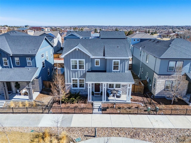 traditional home with a fenced front yard, a residential view, board and batten siding, and a patio