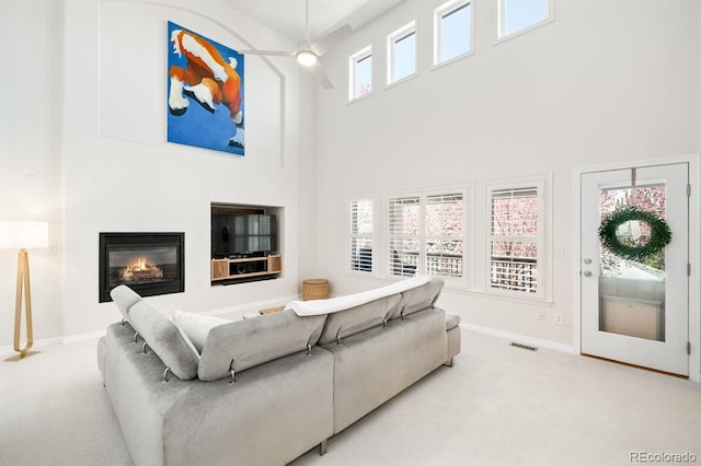 living area featuring a high ceiling, visible vents, baseboards, and carpet
