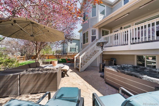 view of patio / terrace featuring an outdoor hangout area, fence, a hot tub, and stairs