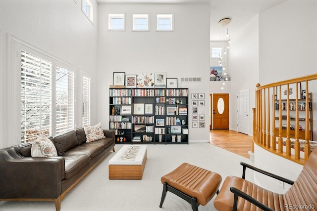 living room featuring a high ceiling, baseboards, visible vents, and carpet floors