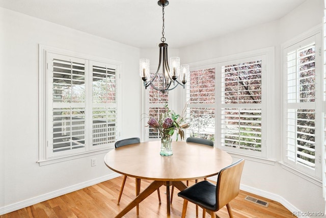 dining space with light wood-style flooring, visible vents, baseboards, and a chandelier