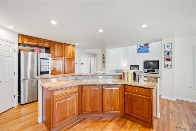 kitchen featuring arched walkways, recessed lighting, light stone countertops, smart refrigerator, and light wood-style flooring