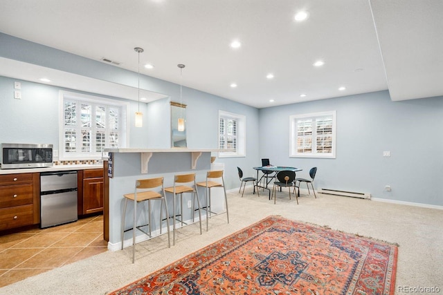kitchen with visible vents, a baseboard radiator, stainless steel microwave, brown cabinetry, and a breakfast bar area