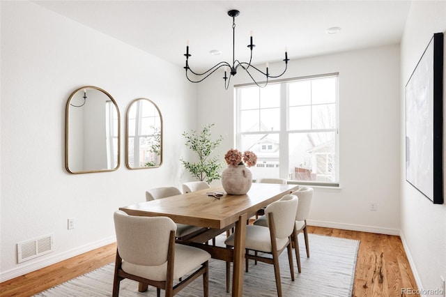 dining area with an inviting chandelier and light hardwood / wood-style flooring