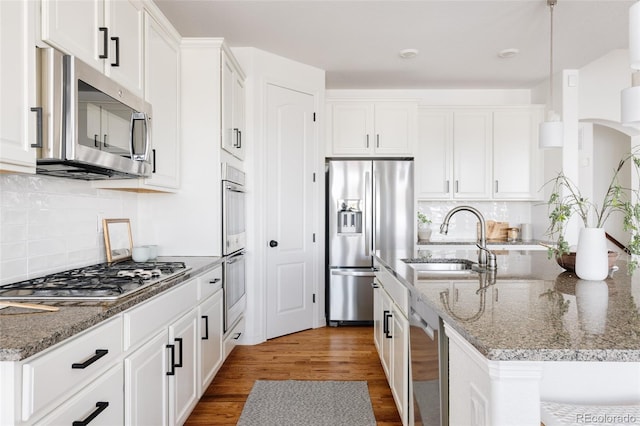 kitchen featuring sink, decorative light fixtures, white cabinets, and appliances with stainless steel finishes