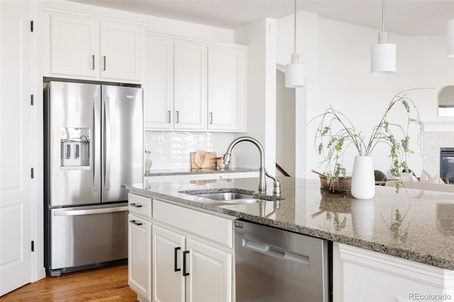 kitchen with sink, stainless steel appliances, white cabinets, and stone counters