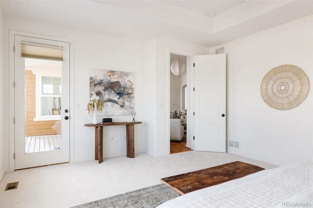 bedroom featuring ensuite bath, a raised ceiling, and light carpet