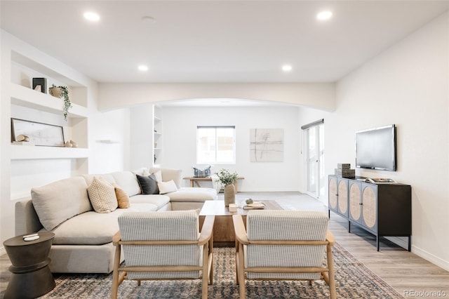 living room featuring built in features and light wood-type flooring