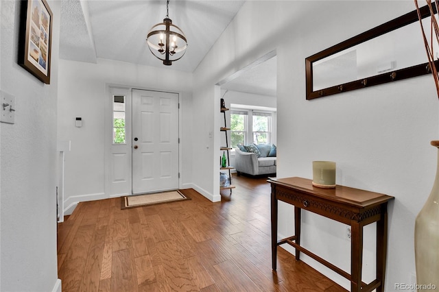 entryway featuring a chandelier, wood finished floors, and baseboards