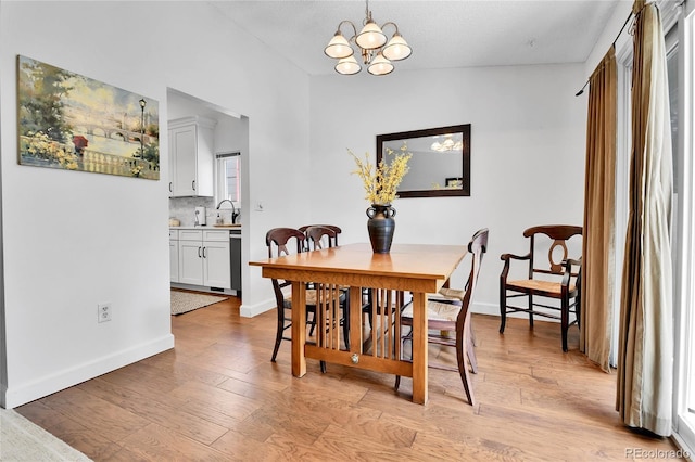 dining area with baseboards, a chandelier, and light wood-style floors