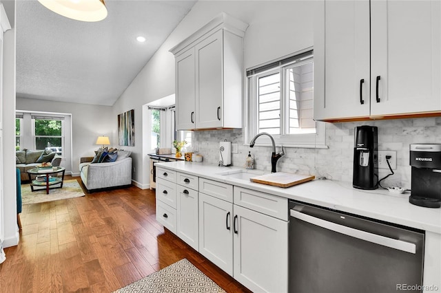 kitchen featuring stainless steel dishwasher, vaulted ceiling, open floor plan, a sink, and dark wood-style floors
