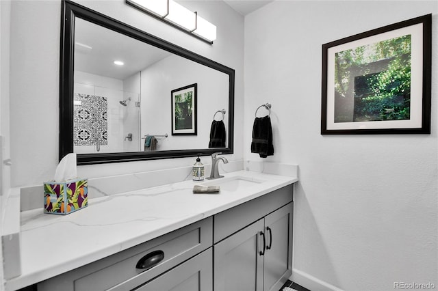 bathroom with vanity, tiled shower, and baseboards