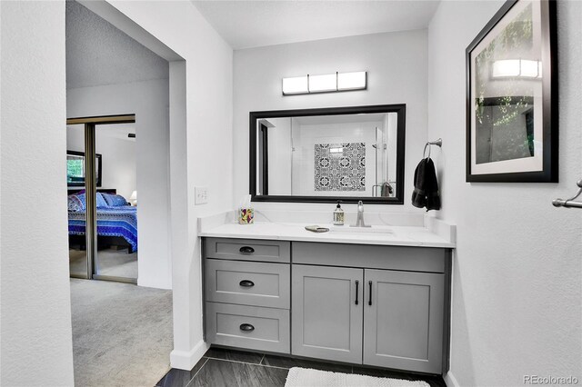ensuite bathroom featuring vanity, a shower, and baseboards
