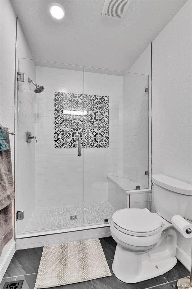 bathroom with toilet, a stall shower, and baseboards