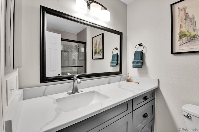 bathroom featuring toilet, a stall shower, and vanity