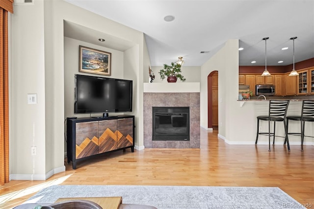 17808 E 104th Pl Unit C, Commerce City, CO 80022 - living area with light wood-style floors, arched walkways, a tiled fireplace, and recessed lighting