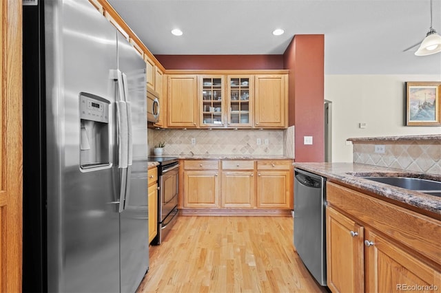 17808 E 104th Pl Unit C, Commerce City, CO 80022 - kitchen featuring appliances with stainless steel finishes, light wood-style floors, tasteful backsplash, light stone counters, and glass insert cabinets