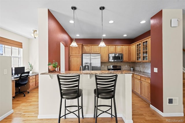 17808 E 104th Pl Unit C, Commerce City, CO 80022 - kitchen with appliances with stainless steel finishes, light wood finished floors, a breakfast bar, light stone counters, and recessed lighting