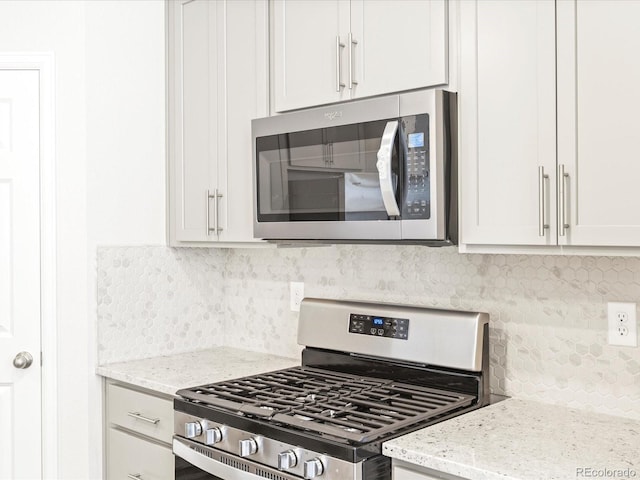 kitchen featuring light stone counters, stainless steel appliances, tasteful backsplash, and white cabinets