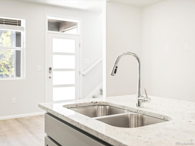 kitchen featuring sink, light stone countertops, and light wood-type flooring