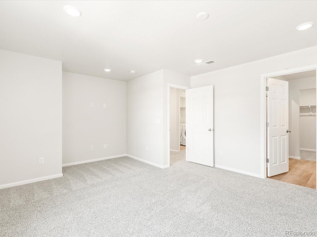 empty room featuring washer / dryer and light colored carpet